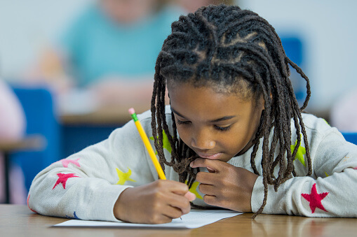 An elementary student works on an assignment in class.